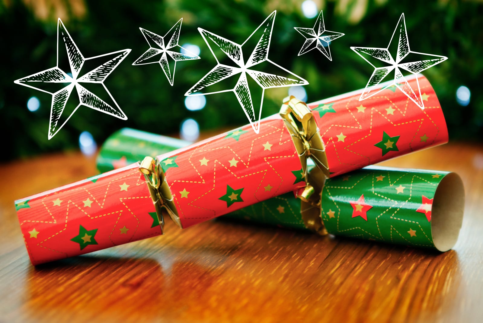Christmas crackers on a table with a tree in the background.