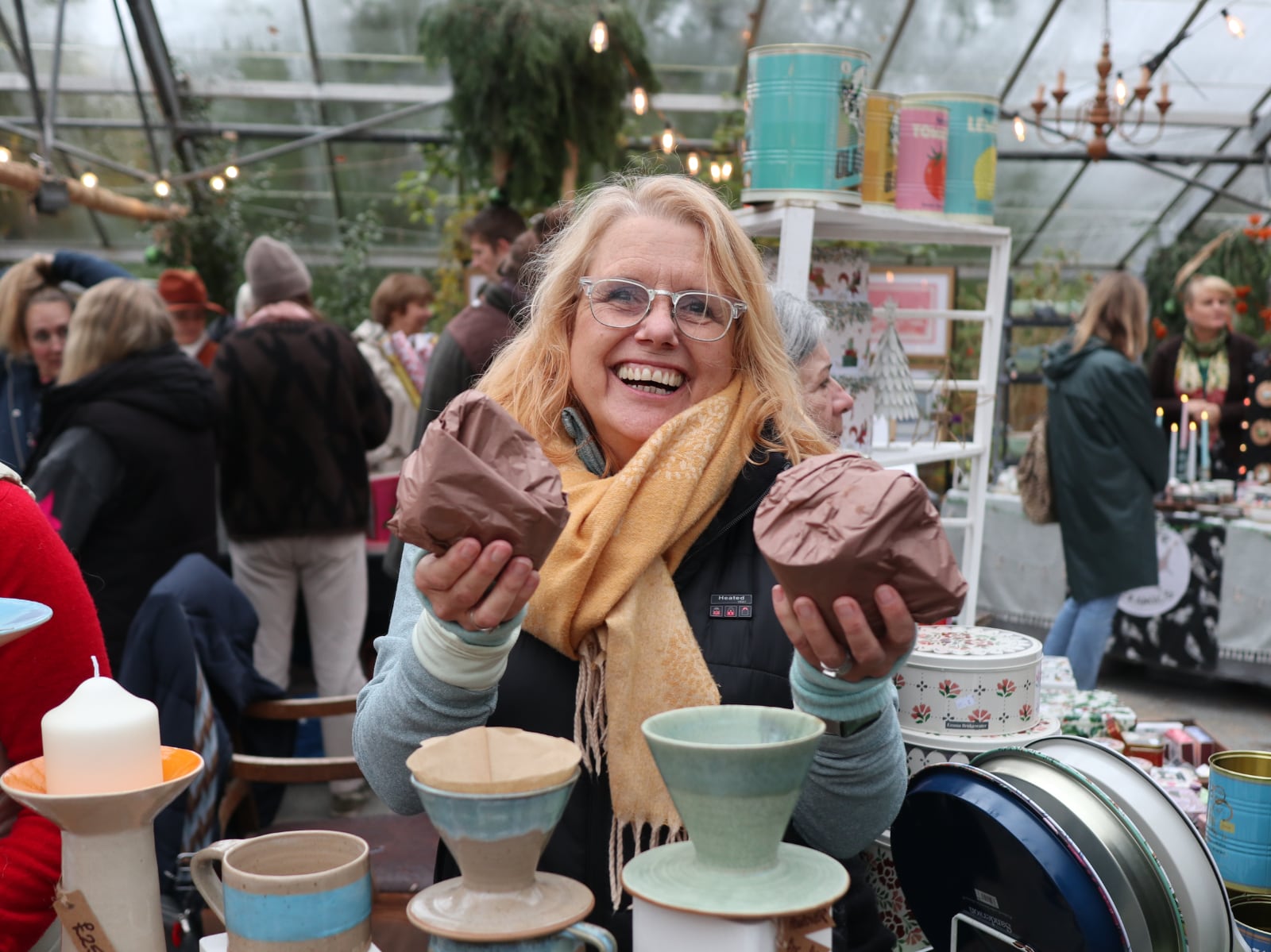 A stallholder holding some of her pottery with a big smile on her face.