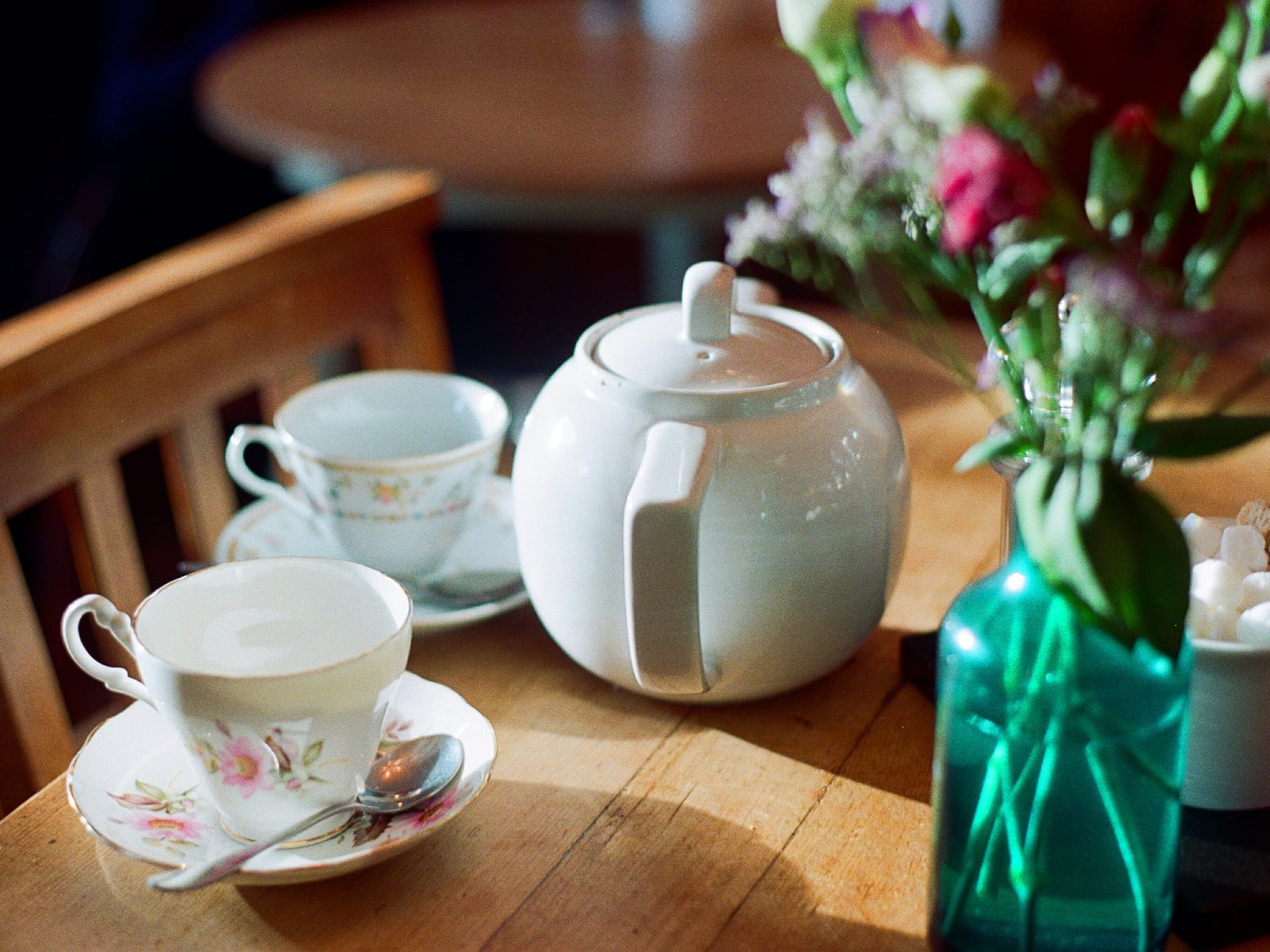 Tea pot and tea cups on a sunny dining table.