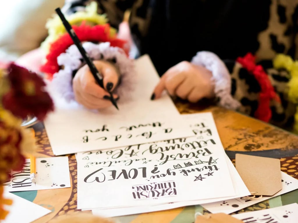 Woman holding a calligraphy pen and writing on paper